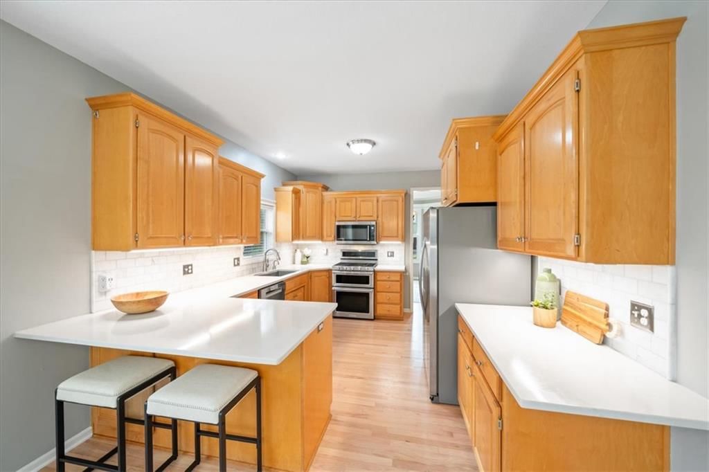 Kitchen island, stainless steel appliances and kitchen backsplash at 10138 Theden Circle, Lenexa, KS 66220