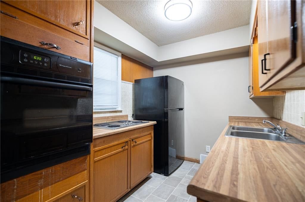 Electric range, kitchen backsplash and black appliances at 5444 N Cypress Avenue, Kansas City, MO 64119