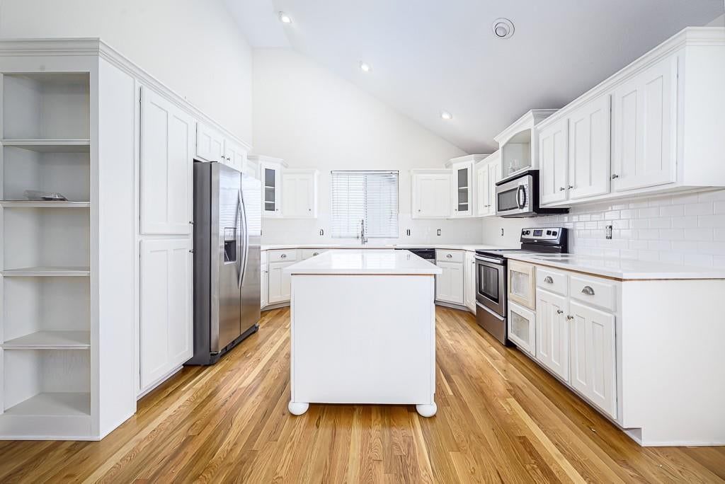 Kitchen island, hardwood floors and white kitchen at 2322 Gettysburg Drive, Leavenworth, KS 66048