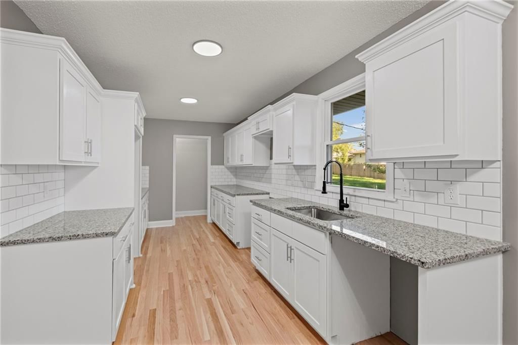 White kitchen, granite counters and shaker cabinets at 11911 Fremont Avenue, Grandview, MO 64030