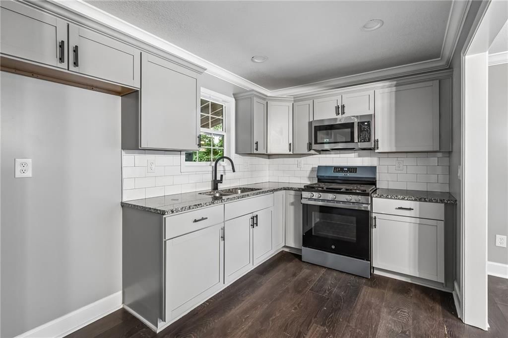 Granite counters, gas range and gray kitchen cabinets at 1514 N 51st Street, Kansas City, KS 66102