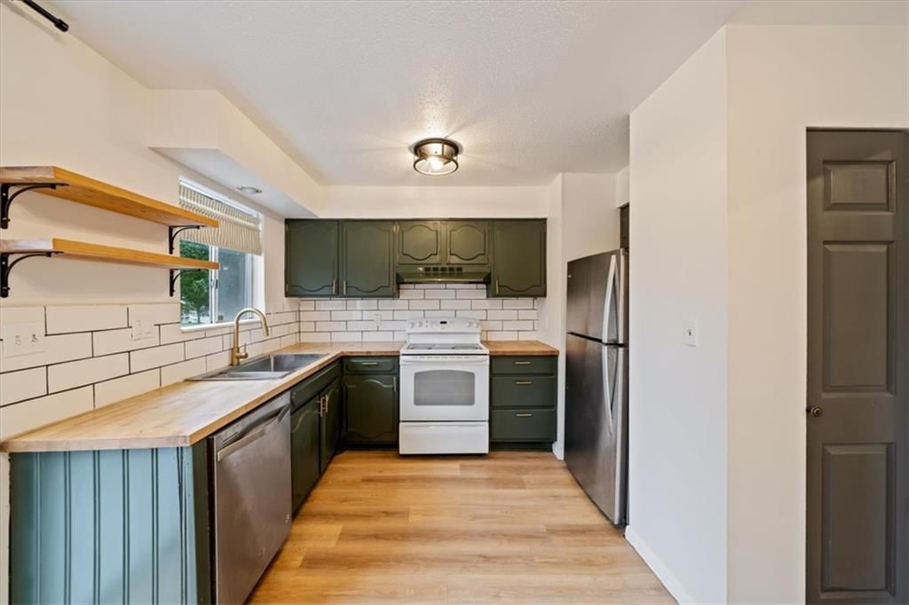 Open floor plan, butcher block countertops and green kitchen cabinets at 8727 Sycamore Avenue, Kansas City, MO 64138
