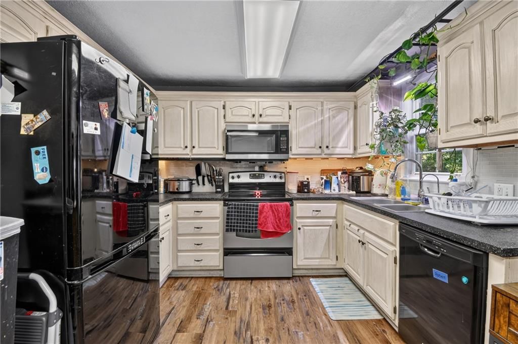 Off-white kitchen cabinets, electric range and kitchen backsplash at 440 W Broadway Street, Peculiar, MO 64078