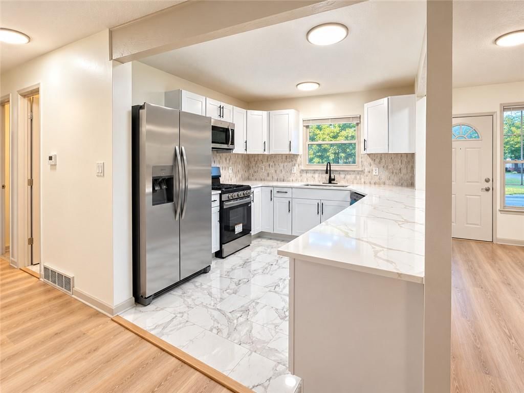 White kitchen, gas range and shaker cabinets at 816 NW Oxford Drive, Independence, MO 64015