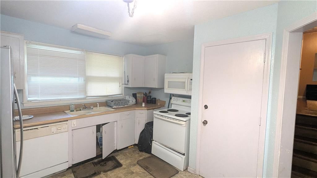 Open floor plan, white kitchen and white appliances at 8507 Spring Valley Road, Raytown, MO 64138