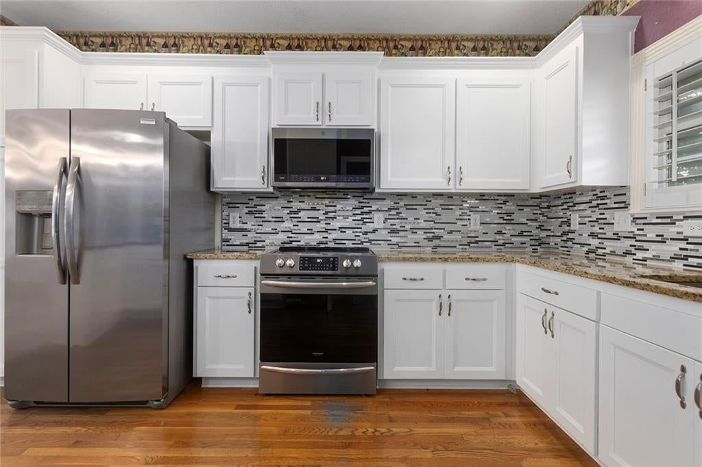 Hardwood floors, white kitchen and granite counters at 12133 S Valley Road, Olathe, KS 66061