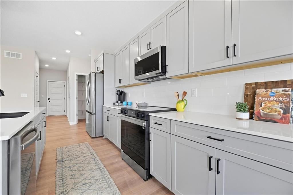Kitchen island, statement lighting and gray kitchen cabinets at 1503 SW 8th Terrace, Oak Grove, MO 64075