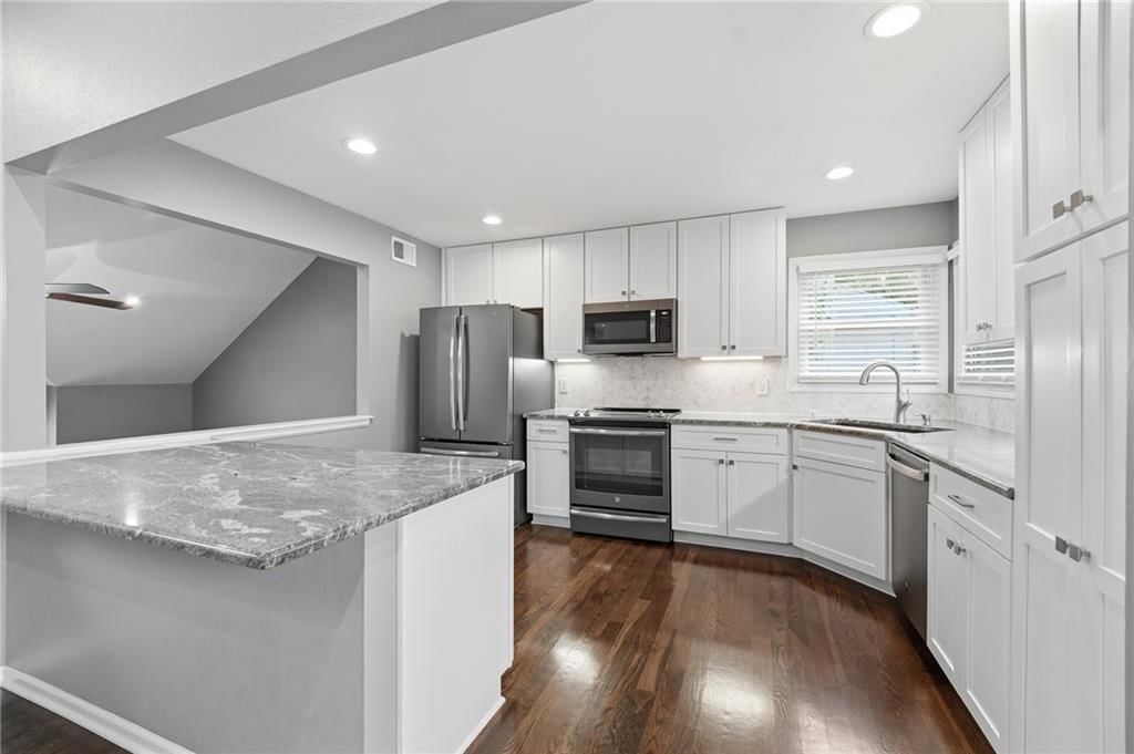 Kitchen island, white kitchen and granite counters at 15762 Horton Street, Overland Park, KS 66223