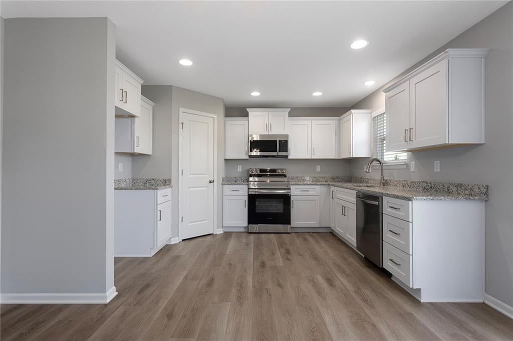 White kitchen, granite counters and shaker cabinets at 510 Foxglove Lane, Raymore, MO 64083