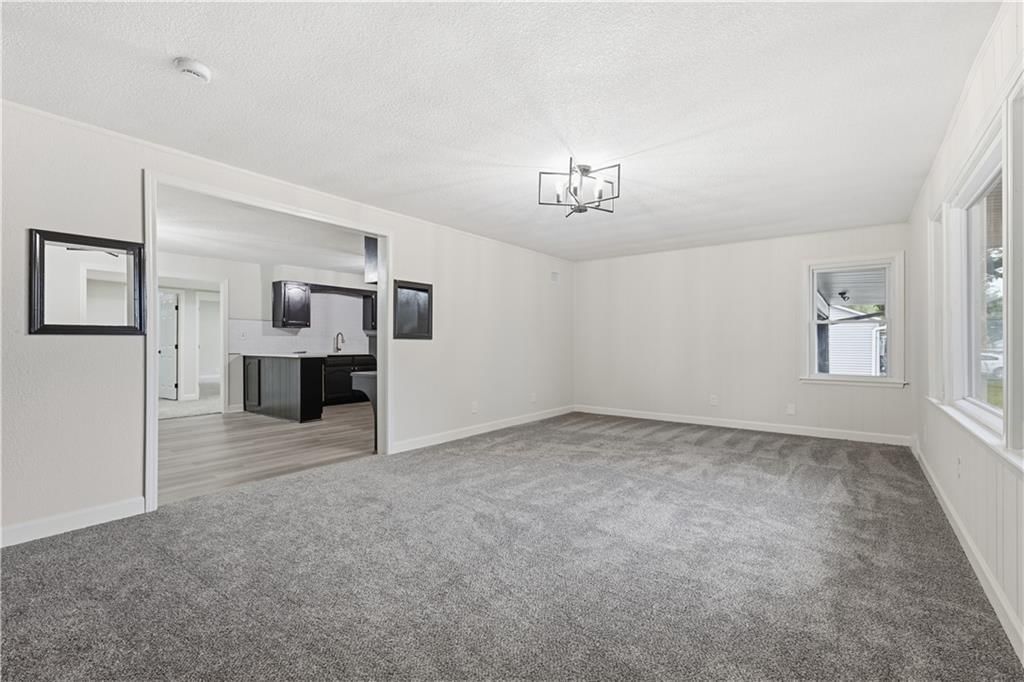Main-floor primary bedroom, statement lighting and white trim at 702 SW Locust Street, Oak Grove, MO 64075