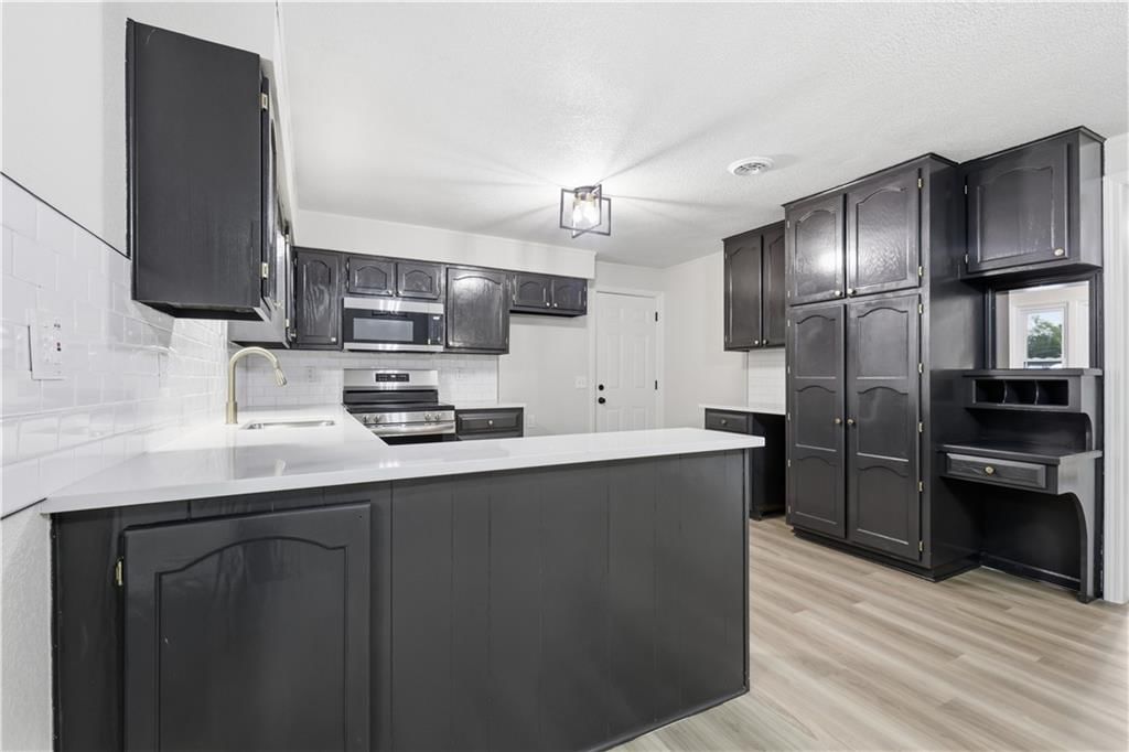 Kitchen island, black kitchen cabinets and stainless steel appliances at 702 SW Locust Street, Oak Grove, MO 64075