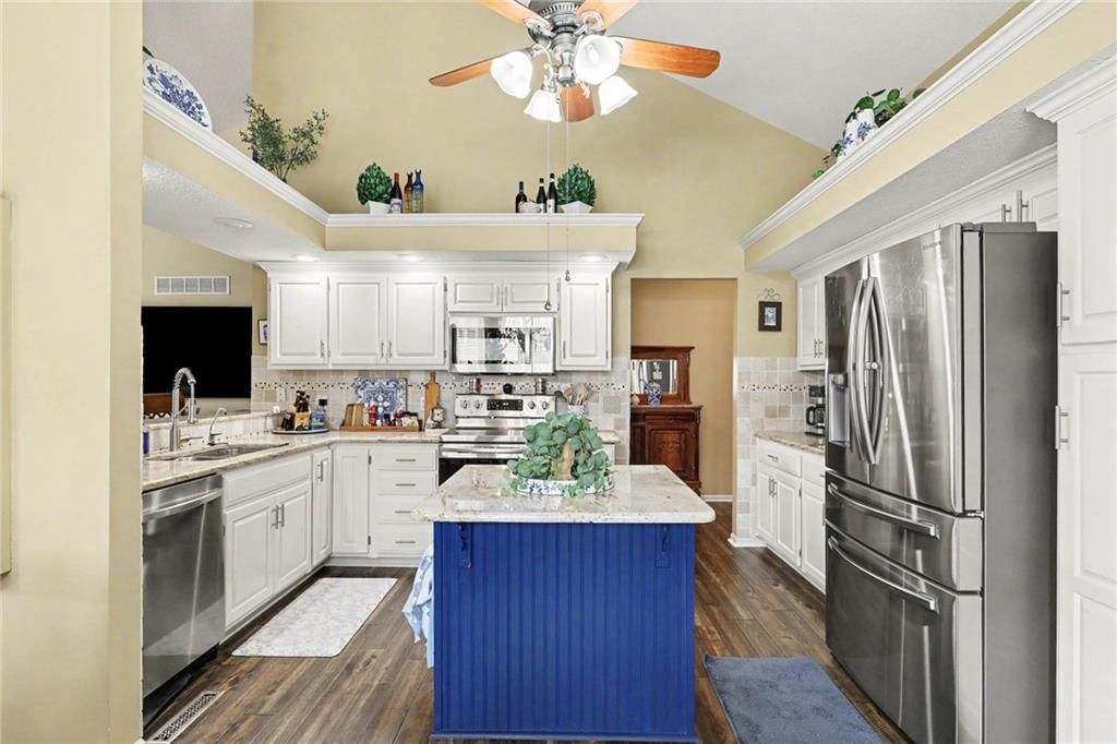 Kitchen island, white kitchen and granite counters at 3213 Devonshire Drive, Platte City, MO 64079
