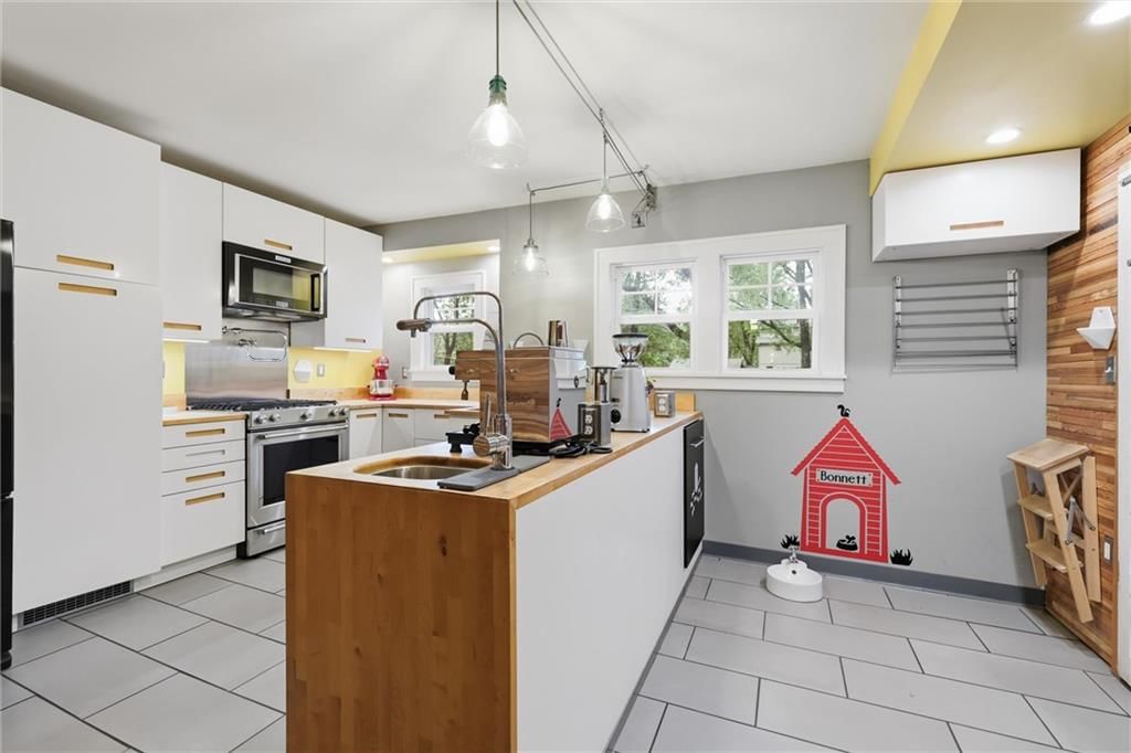 Kitchen island, white kitchen cabinets and gas range at 7516 Locust Street, Kansas City, MO 64131