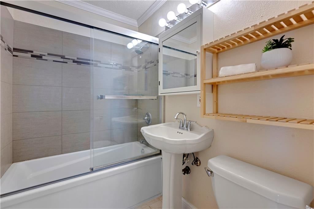 Tiled shower, frameless glass shower and white vanity at 10130 Horton Drive, Overland Park, KS 66207