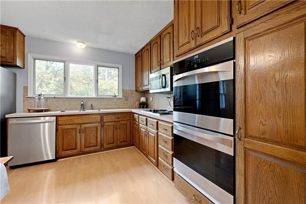 Double oven, stainless steel appliances and wood kitchen cabinets at 10130 Horton Drive, Overland Park, KS 66207