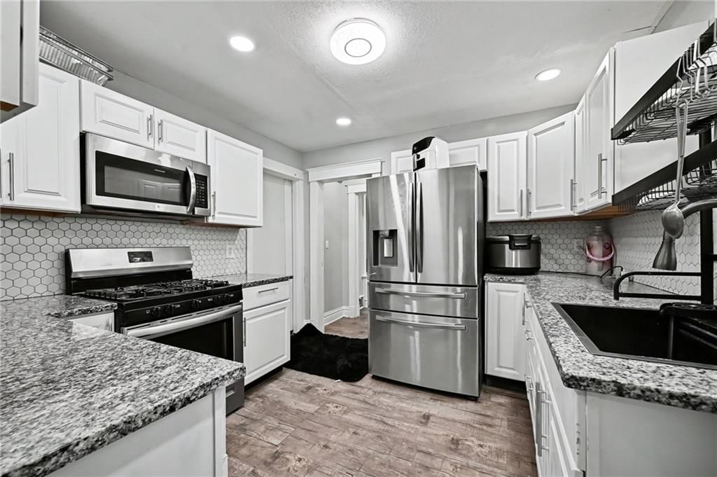 White kitchen, granite counters and shaker cabinets at 801 N 11th Street, Kansas City, KS 66102