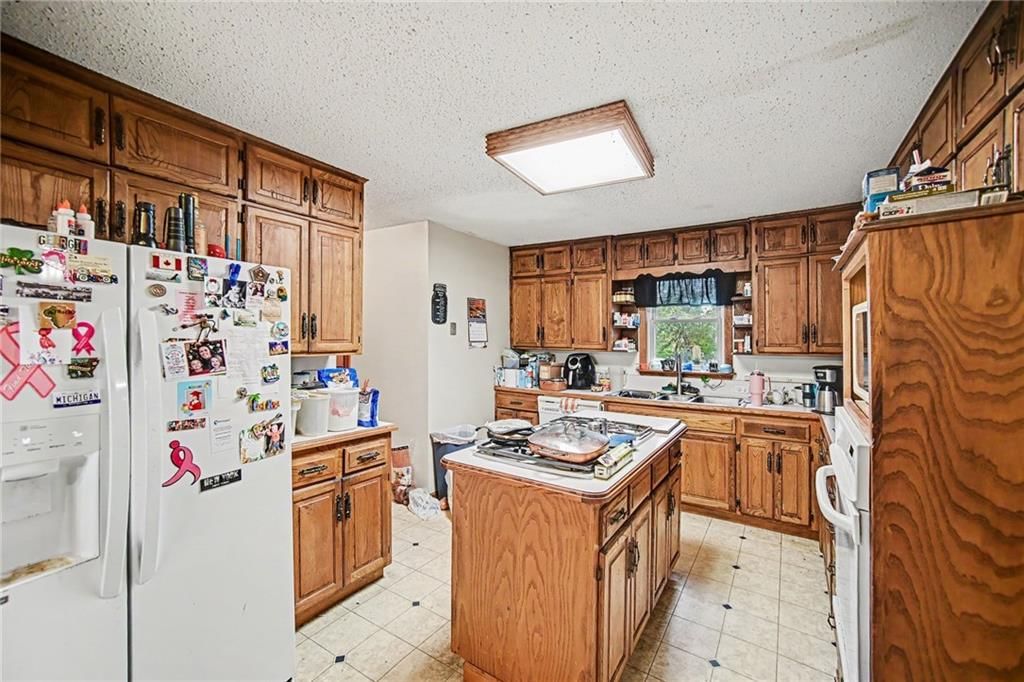 Kitchen island, wood kitchen cabinets and white appliances at 6810 NW Martin Road, Kansas City, MO 64163