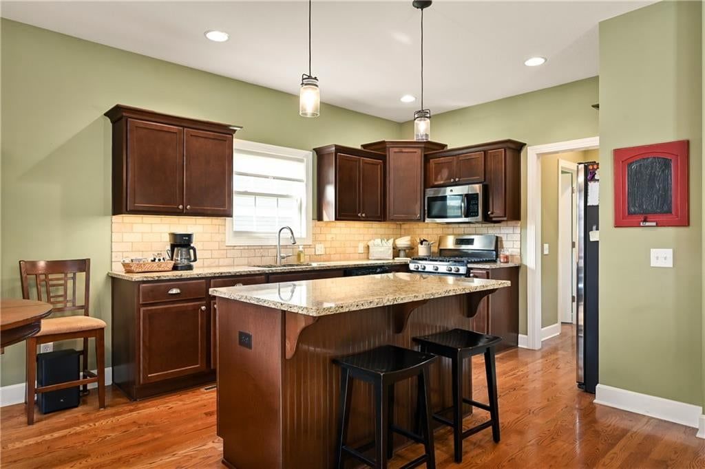 Kitchen island, granite counters and stainless steel appliances at 3317 SW Longview Road, Lee's Summit, MO 64081
