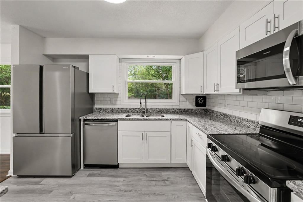 White kitchen, granite counters and shaker cabinets at 8507 Kentucky Avenue, Raytown, MO 64138