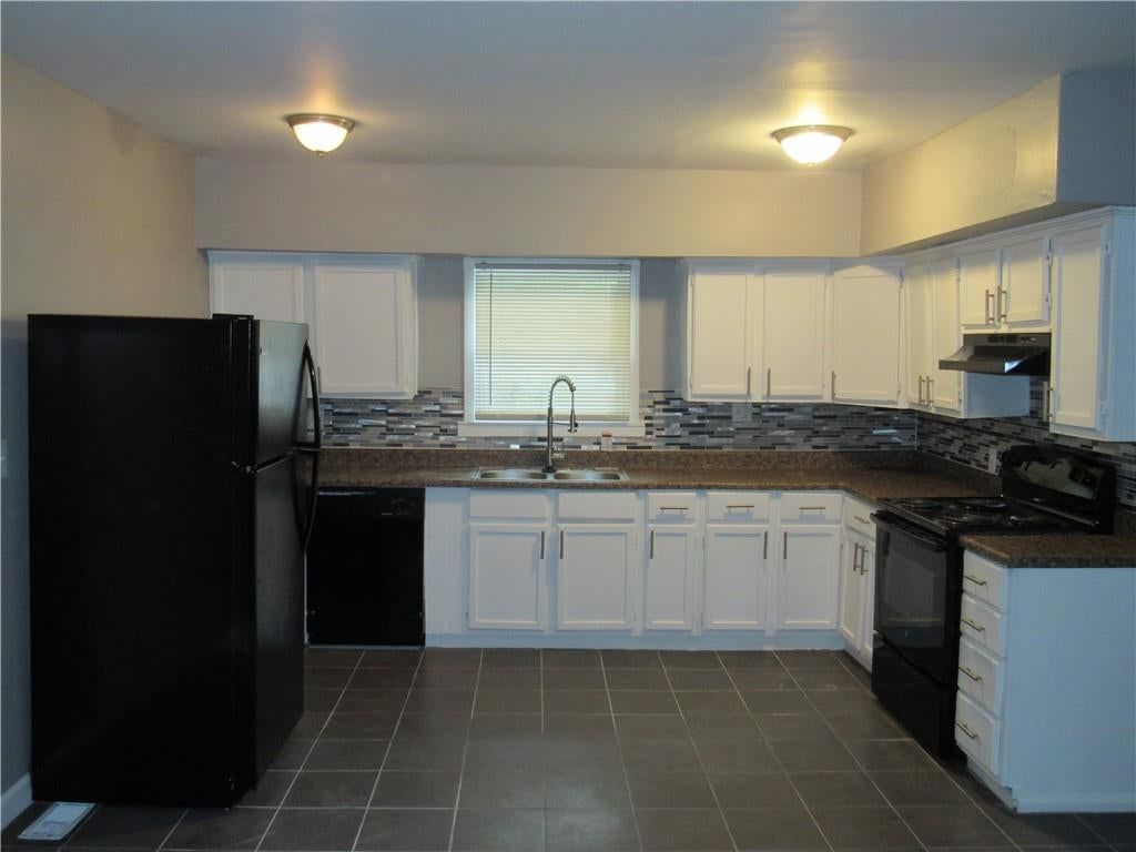 White kitchen, granite counters and tile floors at 5737 INDIANA Avenue, Kansas City, MO 64130