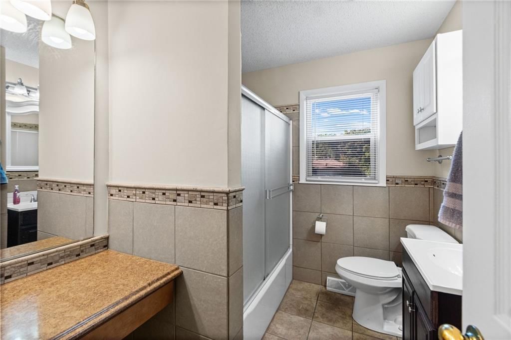 Tiled shower, white vanity and tub and shower combo at 7512 N Baltimore Avenue, Gladstone, MO 64118