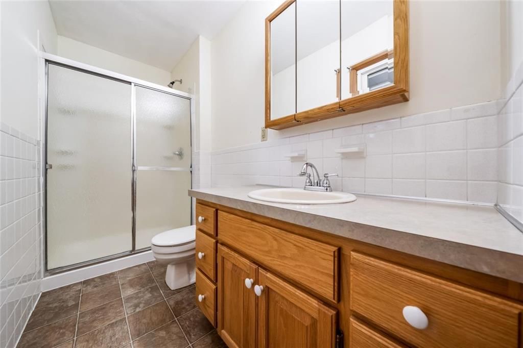 Tiled shower, double vanity and frameless glass shower at 705 SW Mitchell Street, Oak Grove, MO 64075