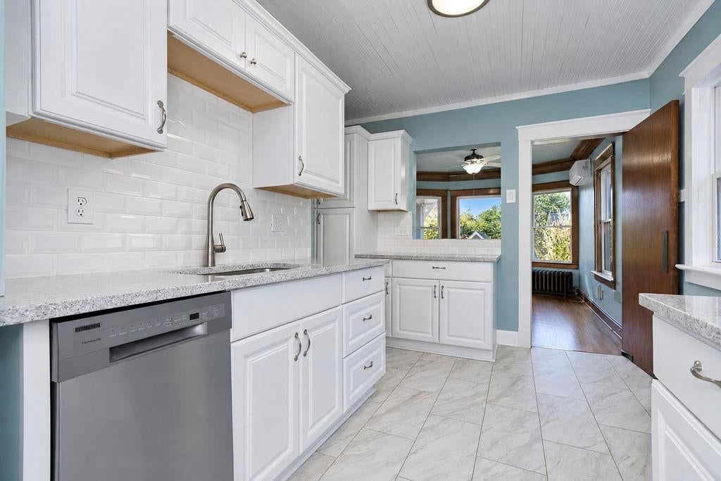 White kitchen, quartz counters and tile floors at 4217 Holmes Street, Kansas City, MO 64110