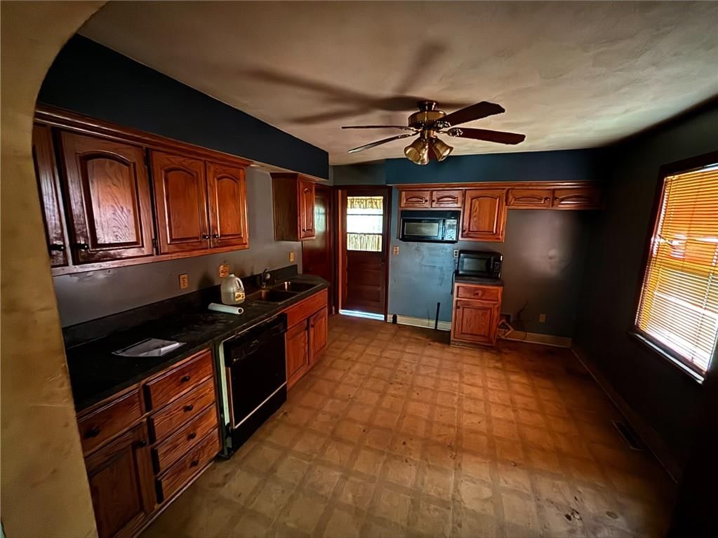 Wood kitchen cabinets, black appliances and black countertops at 710 Pine Street, Belton, MO 64012