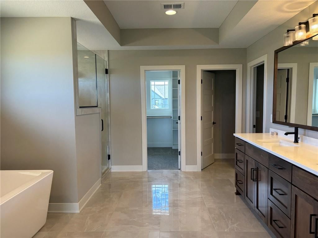 Tile floors, freestanding tub and frameless glass shower at 1816 SW Arbormist Drive, Lee's Summit, MO 64082