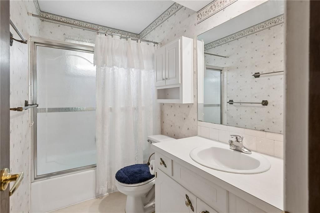 Tiled shower, white vanity and renovated bathrooms at 7413 NW 84th Terrace, Kansas City, MO 64153