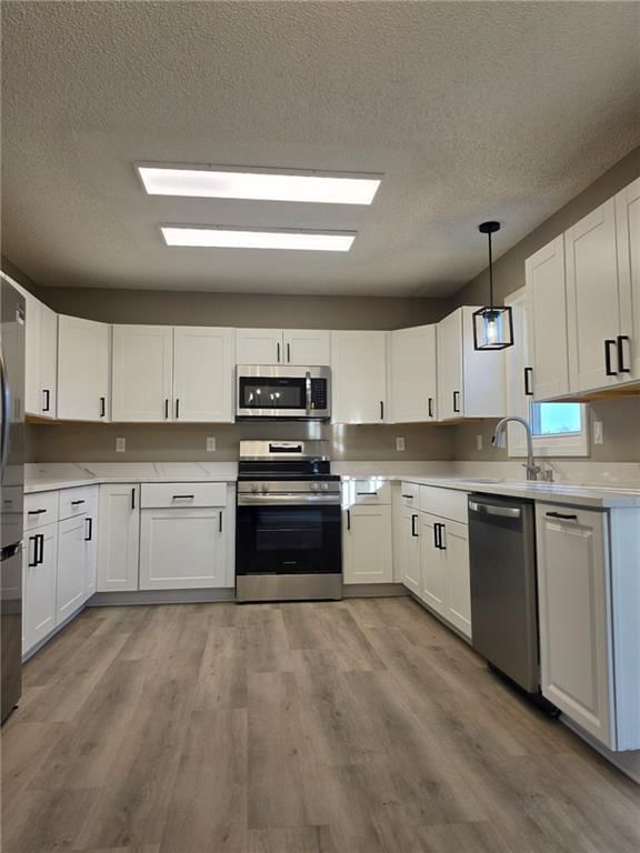 White kitchen, quartz counters and shaker cabinets at 603 SE 21st Street, Oak Grove, MO 64075