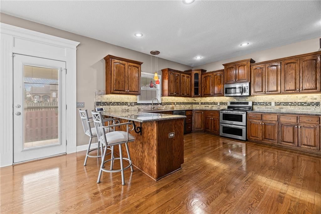Kitchen island, hardwood floors and stainless steel appliances at 1703 NE 181st Terrace, Smithville, MO 64089