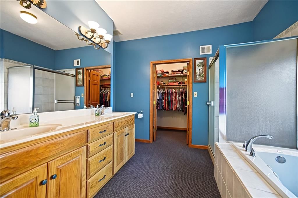 Main-floor primary bedroom, walk-in shower and tiled shower at 12554 Prestwick Lane, Kansas City, KS 66109