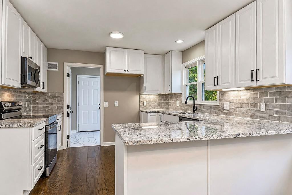 Kitchen island, white kitchen and granite counters at 13811 West 48th Street, Shawnee, KS 66217