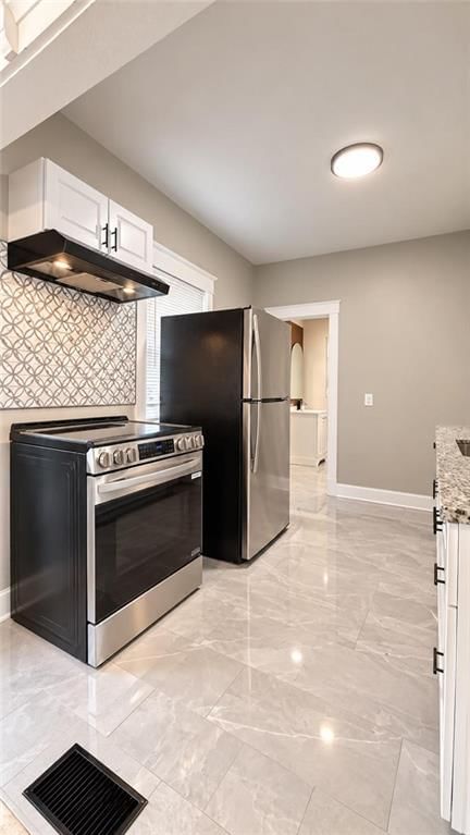 White kitchen, tile floors and stainless steel appliances at 3942 Flora Avenue, Kansas City, MO 64110