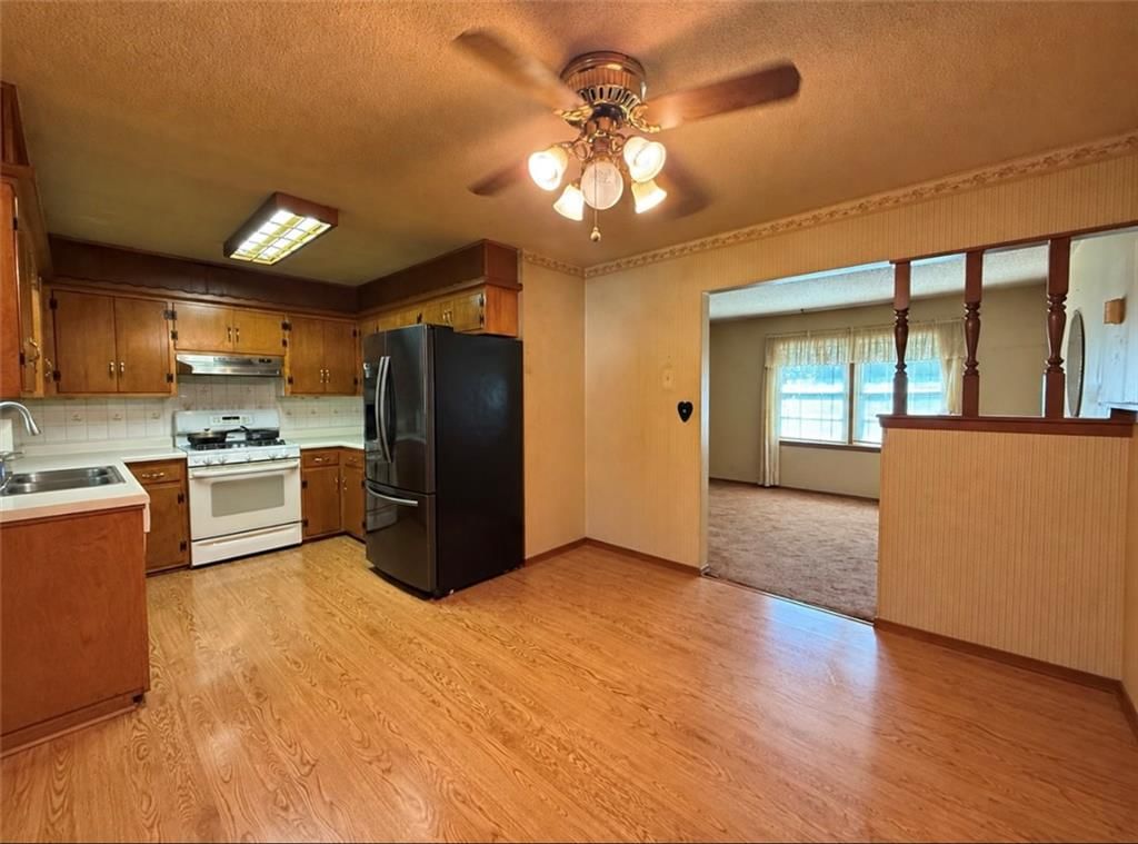 Hardwood floors, wood kitchen cabinets and black appliances at 15400 37th Terrace S, Independence, MO 64055