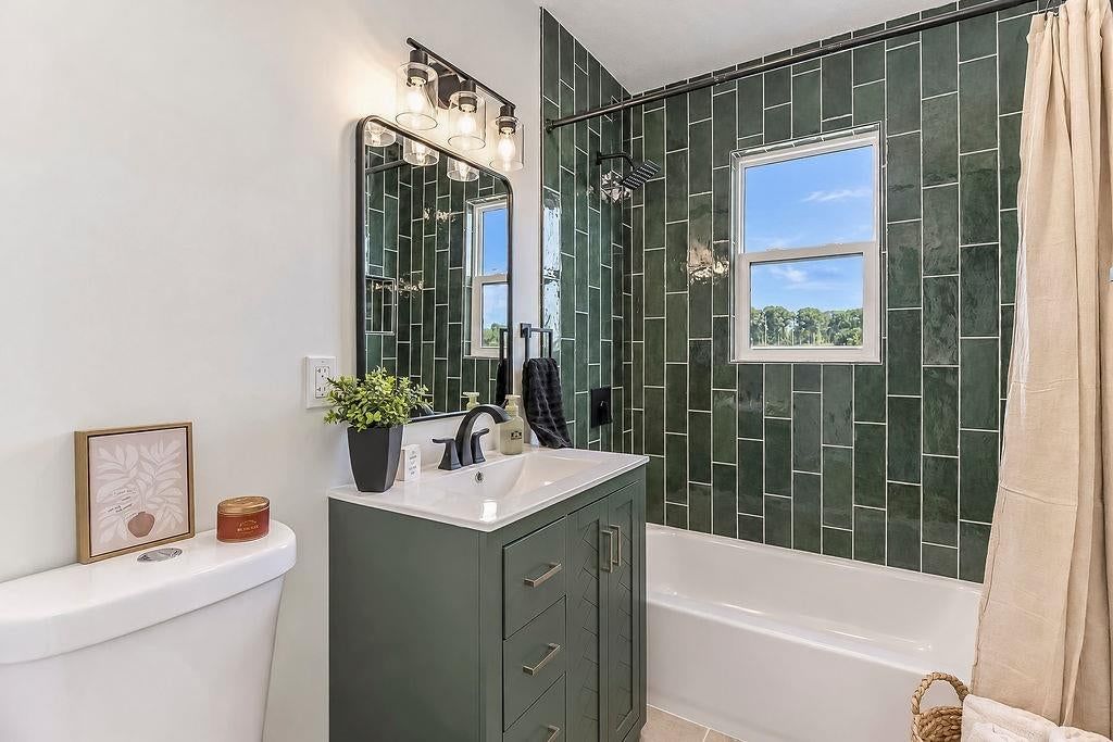 Tiled shower, gray vanity and renovated bathrooms at 3438 N Brighton Avenue, Kansas City, MO 64117
