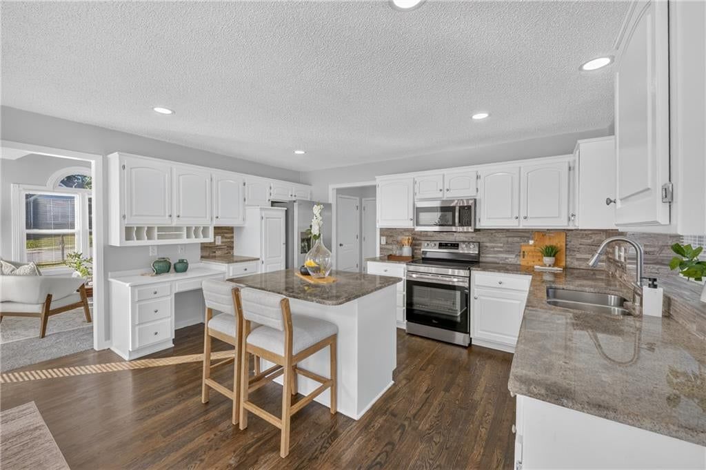Kitchen island, white kitchen and quartz counters at 6529 NW Hidden Valley Road, Kansas City, MO 64152