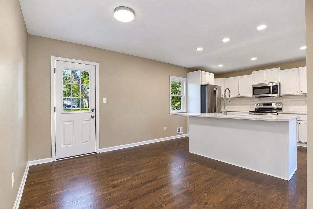 Kitchen open to the living area, kitchen island and white kitchen at 6516 Ballentine Street, Shawnee, KS 66203
