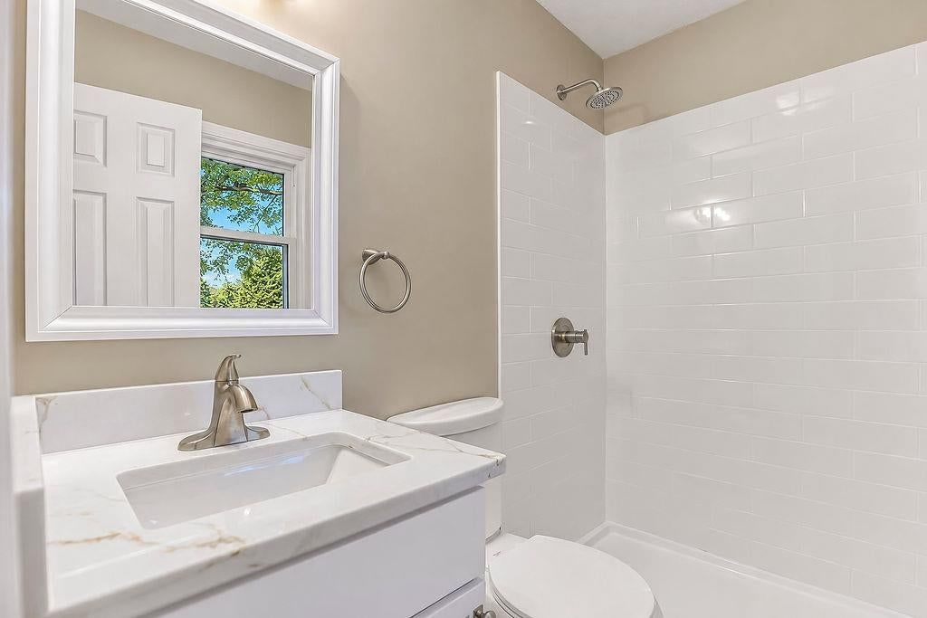 Tiled shower, white vanity and renovated bathrooms at 6516 Ballentine Street, Shawnee, KS 66203
